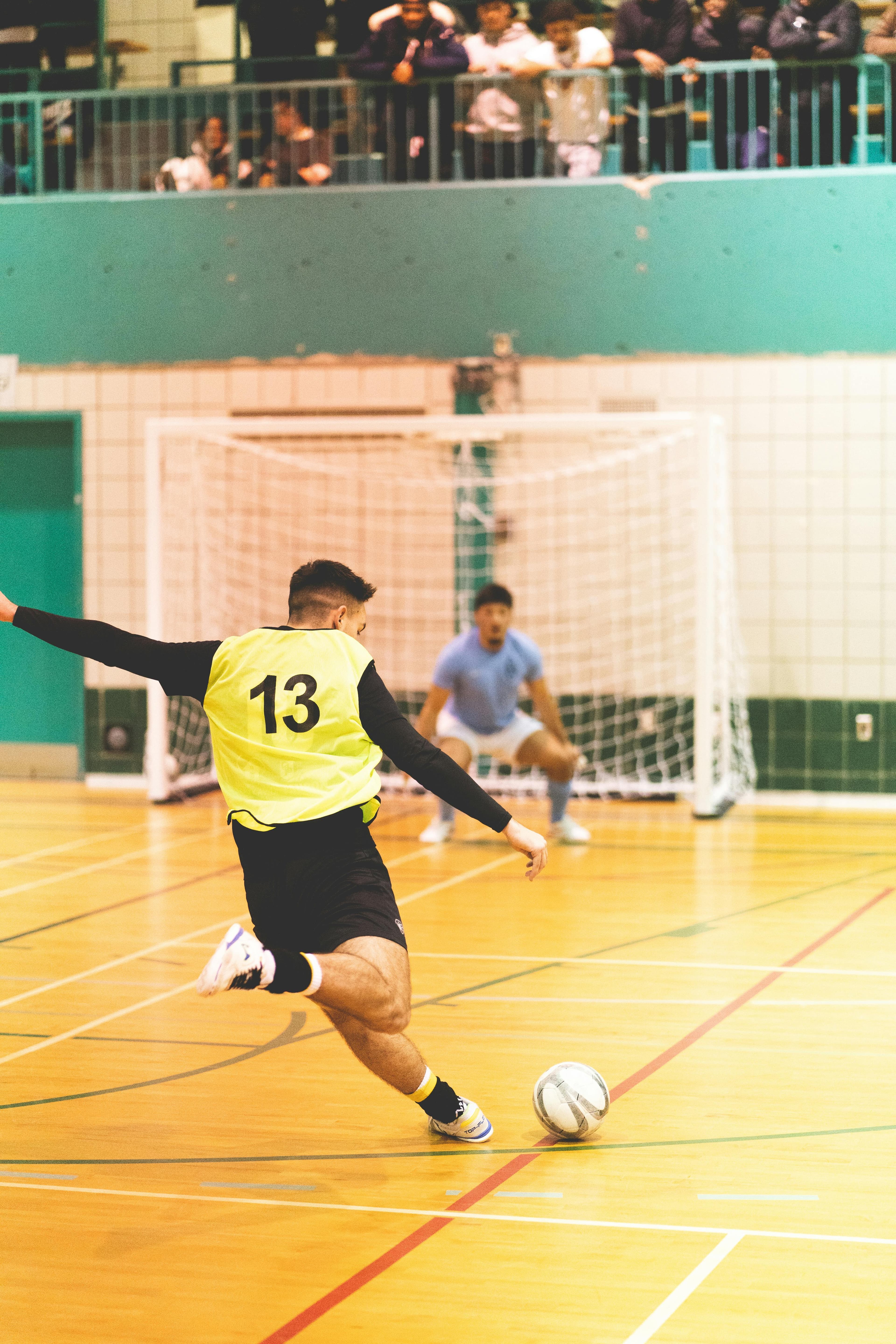 A player striking the ball during an indoor futsal match.